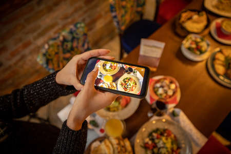 Woman hands taking picture, with smartphone, of the food served in the restaurantの写真素材
