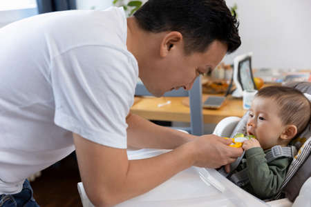 Father giving his baby son teething toyの写真素材