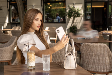 Beautiful young woman taking selfie in a cafe barの写真素材