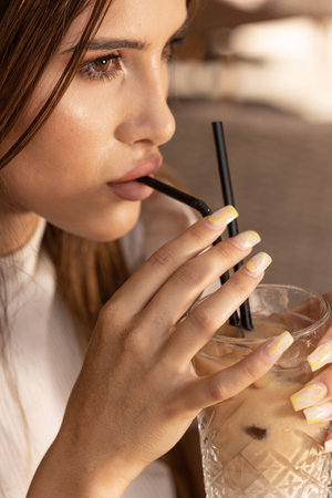 Close up of a young woman drinking coffee with strawの写真素材