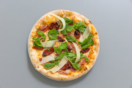 Pizza with arugula prosciutto and dry tomatoの写真素材