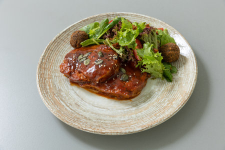 Meat with sauce served with mixed green saladの写真素材