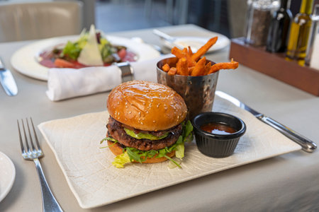 Beef burger served with french fries in the restaurantの写真素材