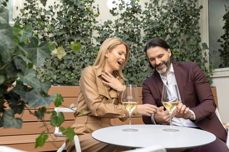 Happy couple drinking wine in the restaurant looking to a smartphone smilingの写真素材