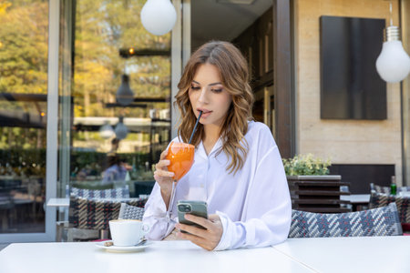 Beautiful woman texting on her smartphone in a cafe barの写真素材