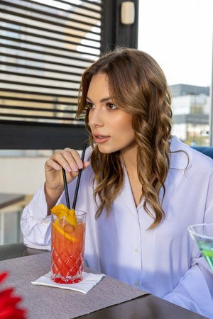 Young woman drinking cocktail alone in the restaurantの写真素材