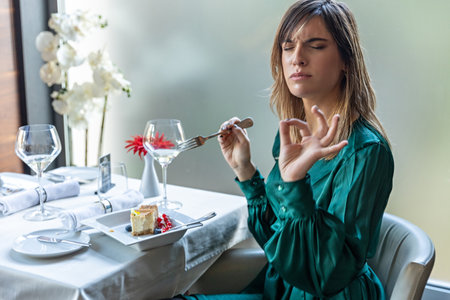 beautiful young woman in green dress sitting at table in restaurant and praying