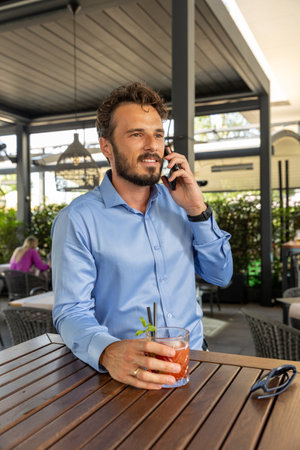 Handsome man talking on the smartphone in outdoor cocktail barの写真素材
