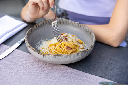 Pasta carbonara served on a plate at a restaurant tableの写真素材