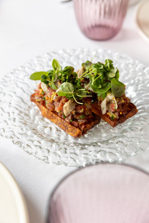 Steak tartare on a bread on a glass plateの写真素材