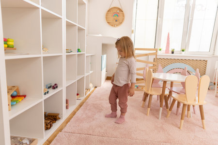 Little girl playing alone in the kindergarten with wooden toysの写真素材
