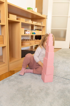 Small girl playing with wooden cubes in the kindergartenの写真素材