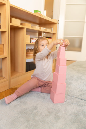 Small girl playing with wooden cubes in the kindergartenの写真素材