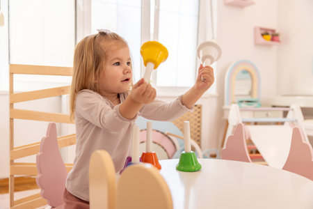 Toddler girl playing with bells in the kindergartenの写真素材