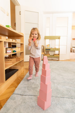Small girl playing with wooden cubes in the kindergartenの写真素材