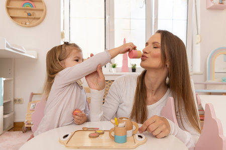 Young girl playing with her mother with wooden toys, eating, drinkingの写真素材