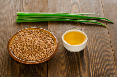 Buckwheat with sunflower seed oil and green onions for dinner on brown wooden backgroundの写真素材