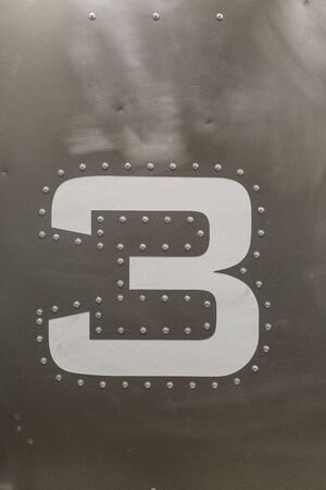 Number three with rivets on grey metal backgroundの写真素材
