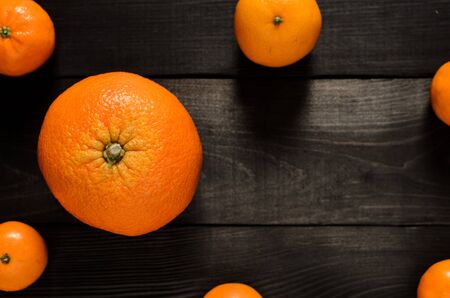 several mandarins and orange isolated on black wooden background