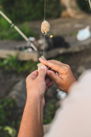 fisherman is preparing fishing tackle. secures the bait to the fishing line at lake