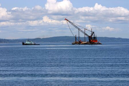 Tow ship is towing barge crane near Alki Beach, Seattleの写真素材