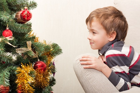 Boy is and looks at  christmas treeの写真素材