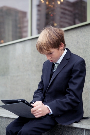 School boy with electronic tablet sitting,outdoorの写真素材
