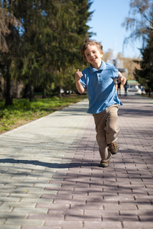 Boy running along road in park, outdoorの写真素材