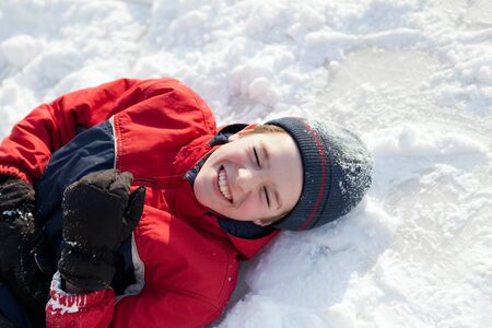 Happy boy in winterwear laughing while playing in snowdrift outsideの写真素材