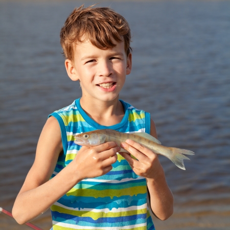 Young boy holding fish and smilingの写真素材