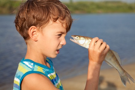 Young boy holding fish and smilingの写真素材