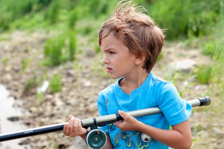 serious boy fishing on river, summerの写真素材