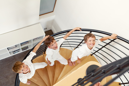 Three happy brother sitting on steps, indoorの写真素材