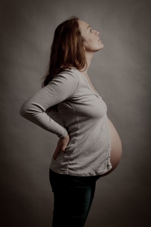 Portrait of beautiful happy pregnant woman in studio, motherhood, monochrome, tummy