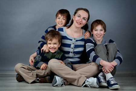 Portrait of happy mother and three sons on gray backgroundの写真素材