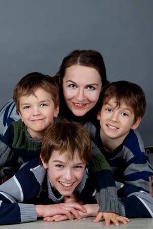 Portrait of happy mother and three sons on gray backgroundの写真素材
