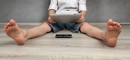 Portrait of boy, playing on tablet on gray background, indoors, studio portrait on gray background,...
