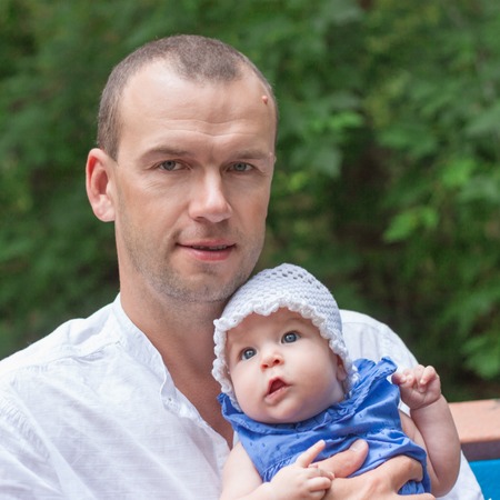portrait of happy father gently hugs little daughter, outdoor