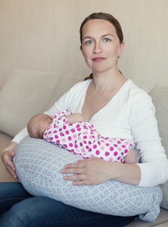 Happy mother breast feeding her newborn in room, indoorの写真素材