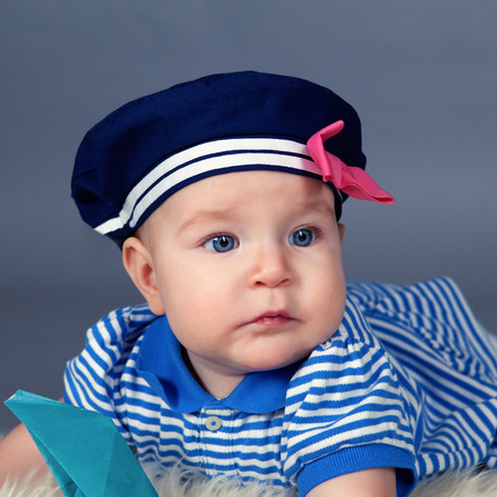 Portrait of happy cute baby girl in sailor dress in studio on  gray backgroundの写真素材