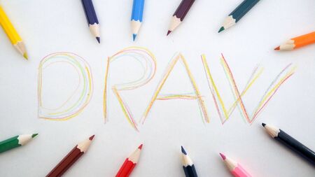 word "draw" writen on a paper surounded all arround with crayonsの写真素材