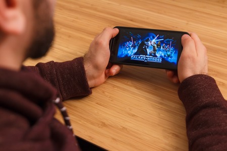PRAGUE, CZECH REPUBLIC - MARCH 16, 2019: Man holding a smartphone and playng the Star Wars: Galaxy...