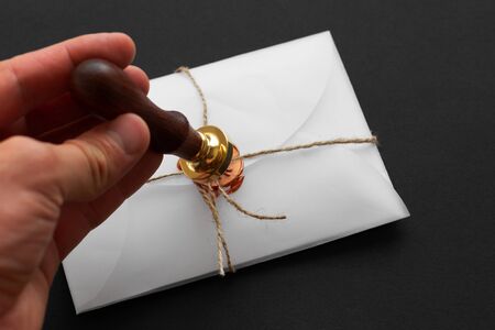Notary public wax stamper. White envelope with brown wax seal, golden stamp. Responsive design mockup, flat lay. Still life with postal accessoriesの写真素材