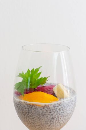 Glass of chia healthy food coconut pudding with banana, mango and dragon fruit on the white background. Healthy conceptの写真素材