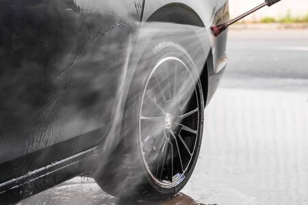 A man is washing a Skoda Rapid wheel at self service car wash. High pressure vehicle washer machine clean with water. Car wash equipment. Mlada Boleslav, 01.12.2019,のeditorial素材