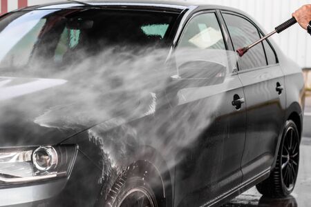 A man is washing a car at self service car wash. High pressure vehicle washer machine clean with water. Car wash equipment. Mlada Boleslav, 10.12.2019のeditorial素材