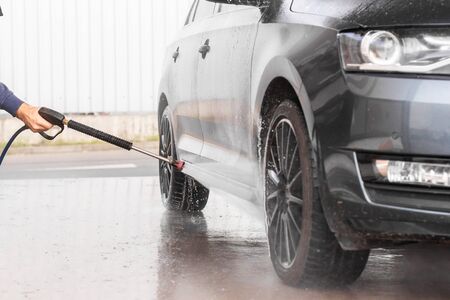 A man is washing a car at self service car wash. High pressure vehicle washer machine sprays foam Mlada Boleslav, 10.12.2019のeditorial素材