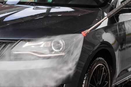 A man is washing a car at self service car wash. High pressure vehicle washer machine clean with water. Car wash equipment. Mlada Boleslav, 10.12.2019のeditorial素材