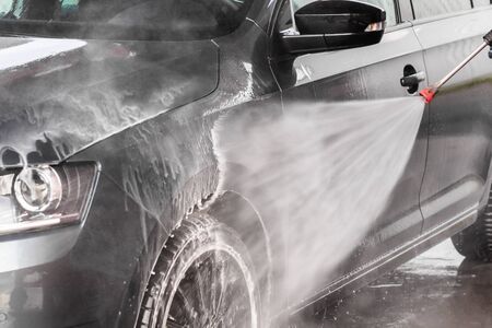 A man is washing a car at self service car wash. High pressure vehicle washer machine clean with water. Car wash equipment. Mlada Boleslav, 10.12.2019のeditorial素材