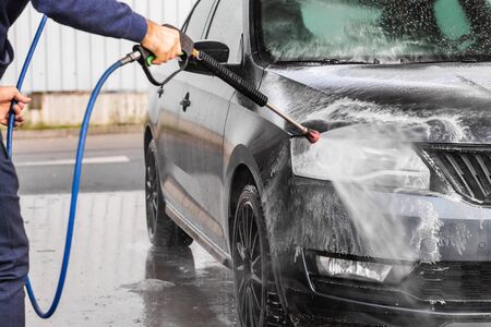 A man is washing a car at self service car wash. High pressure vehicle washer machine sprays foam Mlada Boleslav, 10.12.2019のeditorial素材